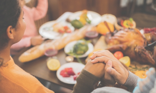 Family members hold hands at the dinner table