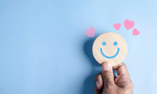 Person holding a smiley face on a blue background