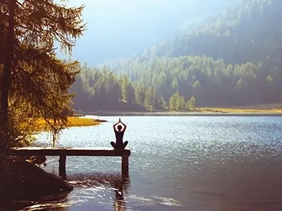 Person doing yoga on a lake dock